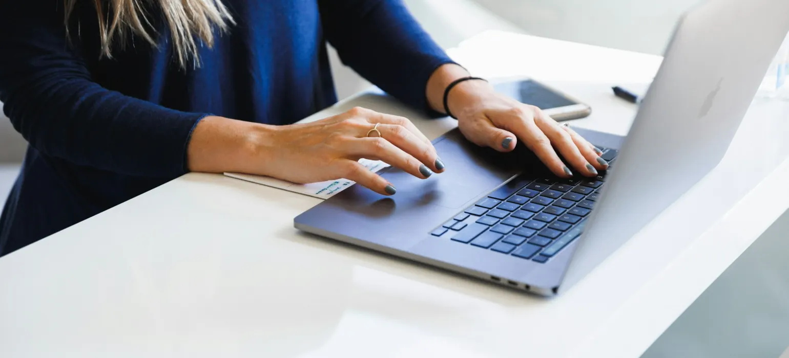 Person typing on a laptop at a white desk