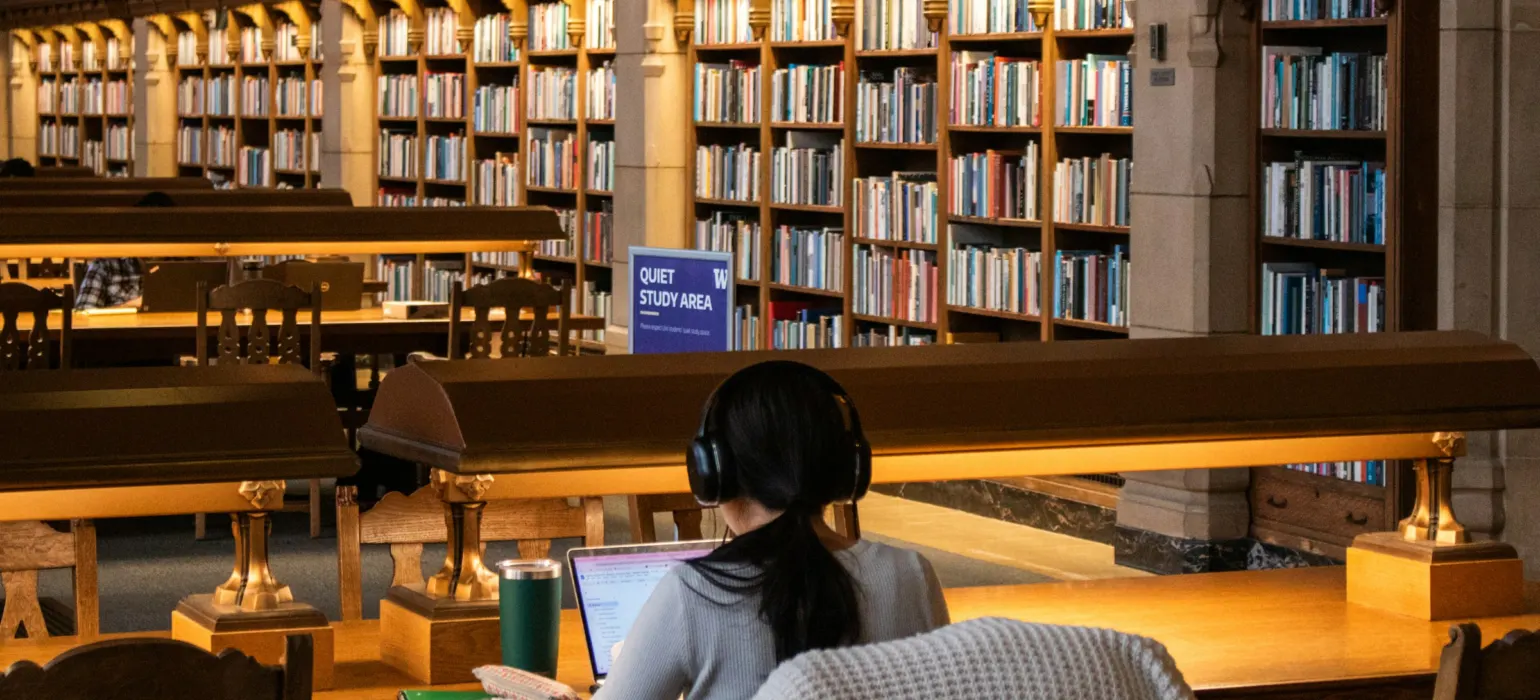 Student studying on a laptop in a library reading room