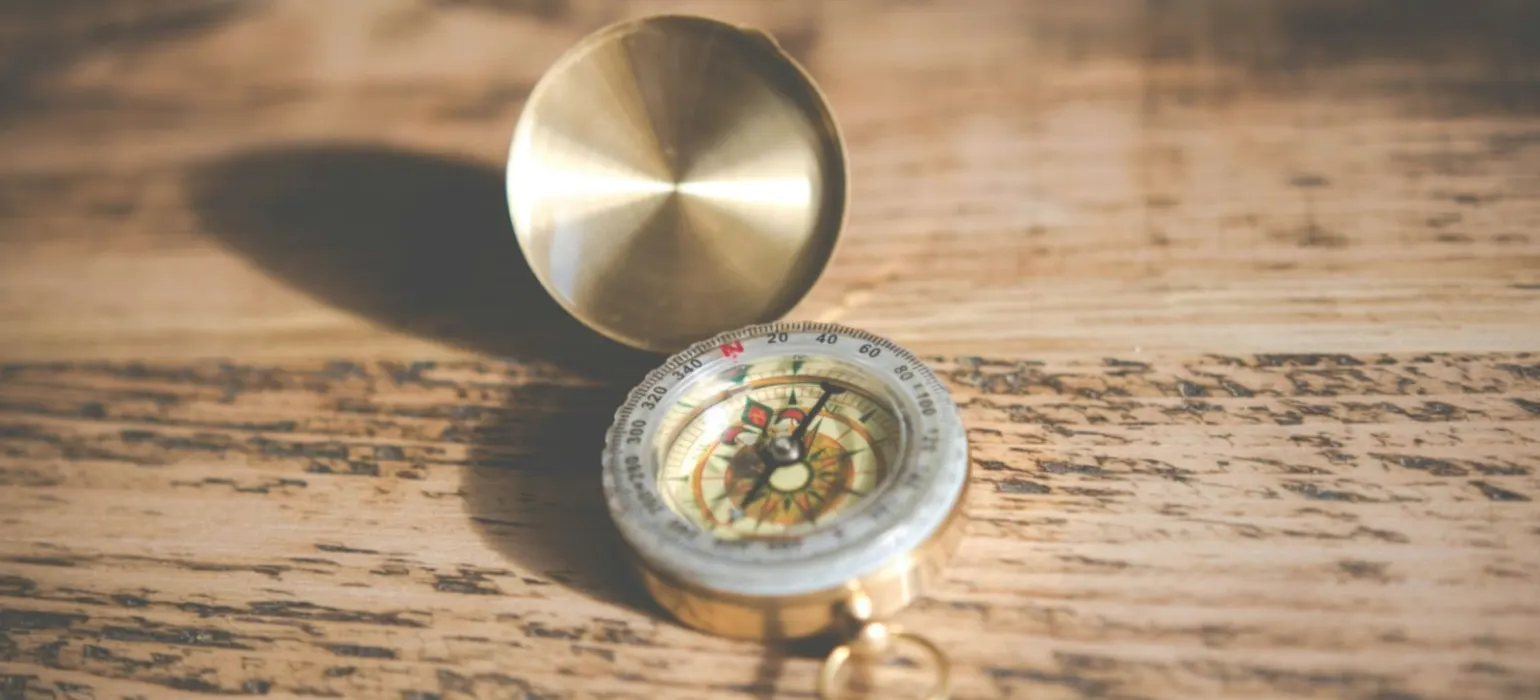 Shallow focus photography of compass on brown table