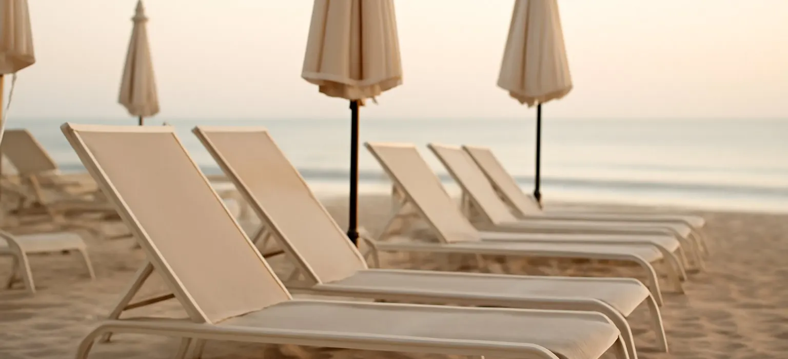 Rows of empty lounge chairs by a resort pool in soft morning light