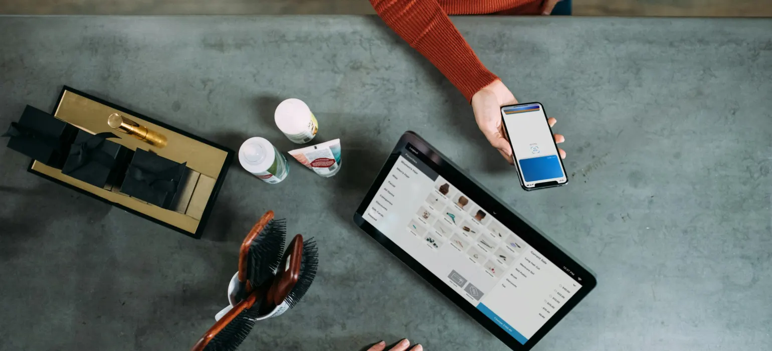 Person holding smartphone beside tablet computer