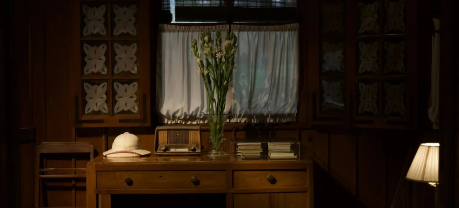 Desk with hat, radio, and flowers in room