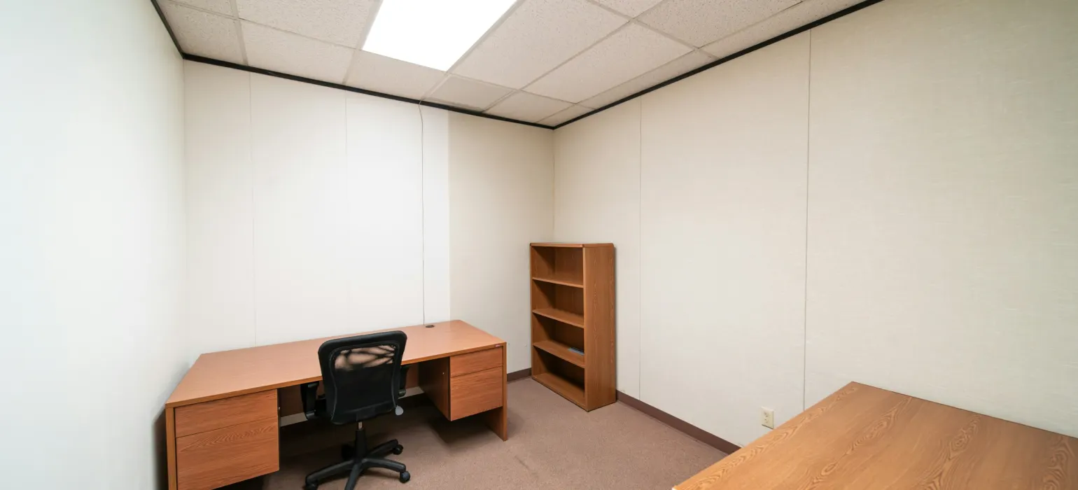 An empty room with a desk and a book shelf